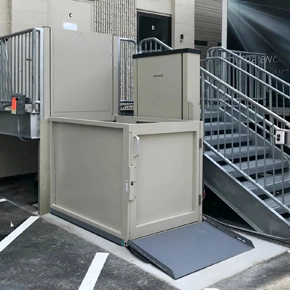 Vertical platform lift installed alongside a set of metal stairs.