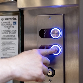 A person calling a Savaria V-1504 vertical platform lift cab to the first floor.