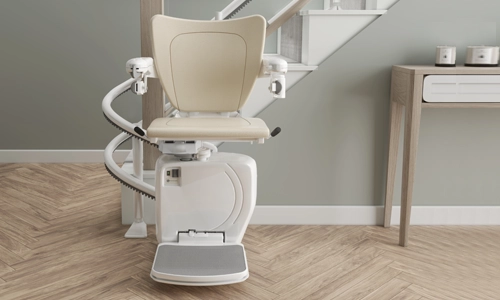A Handicare 4000 curved stairlift stationed at the bottom landing next to a console table.