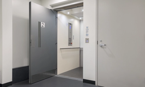 A white and gray Prolift vertical platform lift with a gray open door.