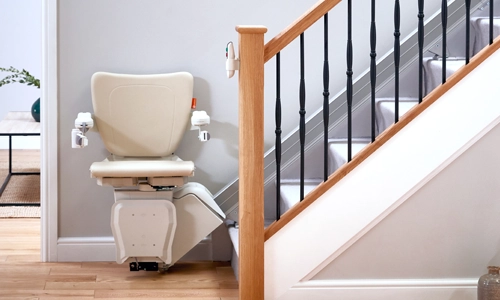 A Handicare 1100 Straight stairlift stationed at the bottom landing of a staircase.
