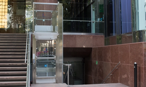 A Multi-level Glass enclosure of a Savaria V-1504 vertical platform lift installed outdoors.