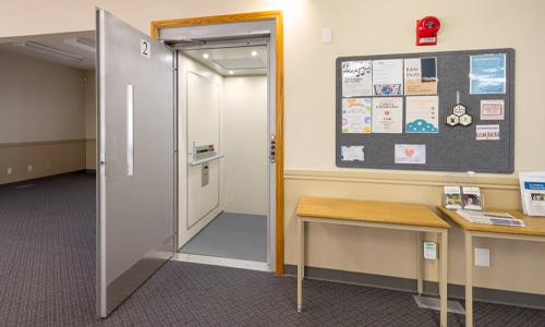A V-1504 vertical platform lift with a white interior installed in an institution.