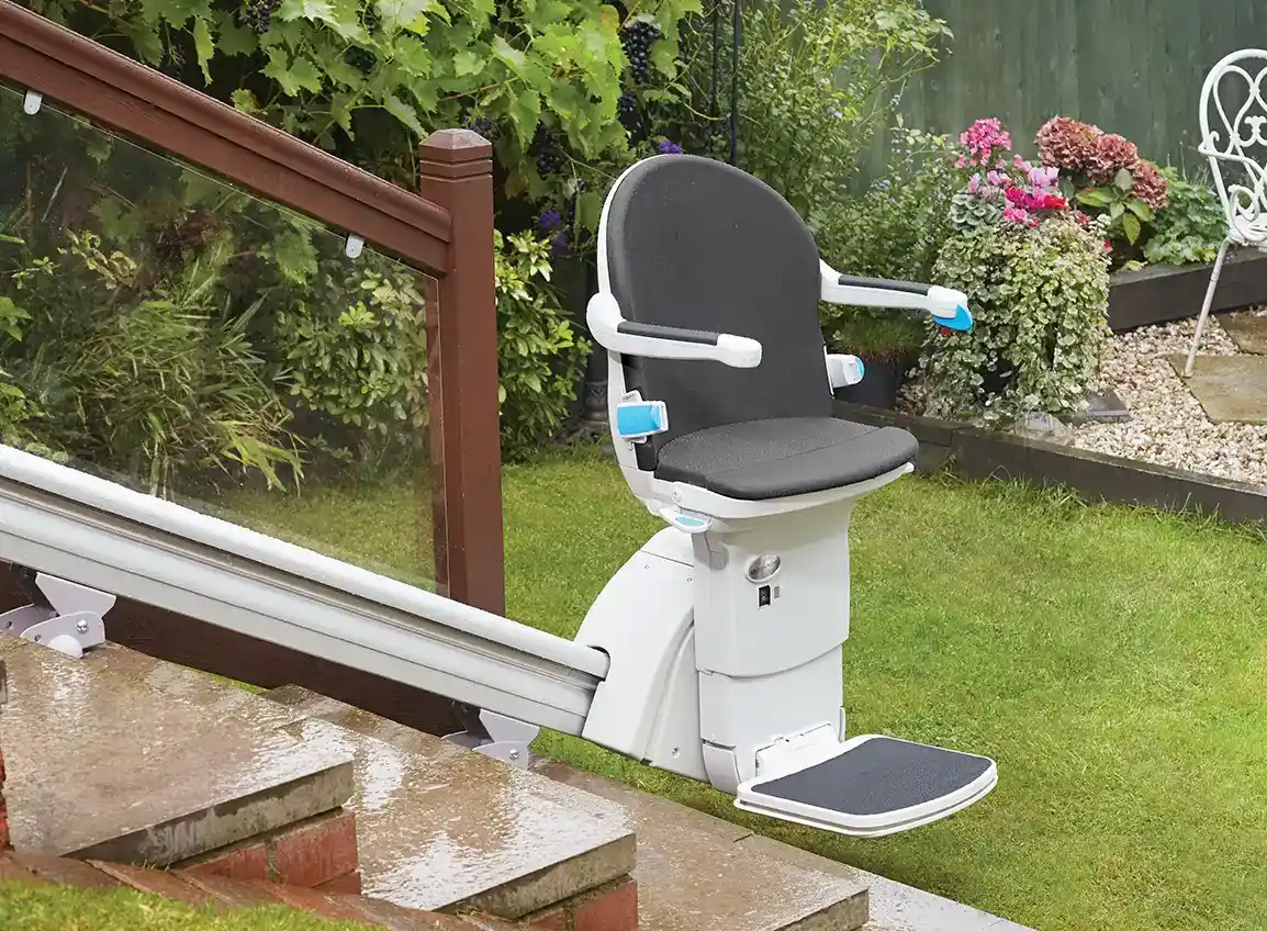 Handicare 1000 outdoor stair lift with slate Smart seat and key switch in a garden