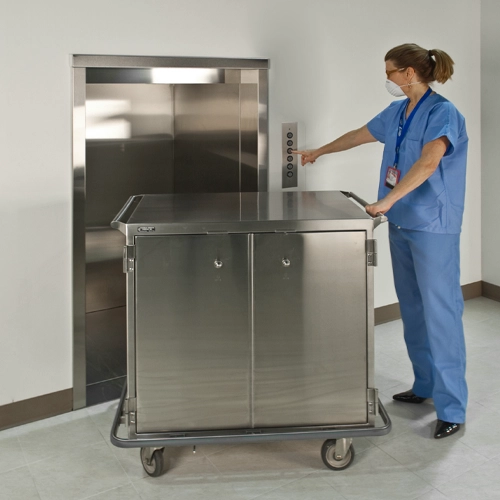 Medical professional transporting equipment in a hospital using a material lift, ensuring safe and efficient handling of sensitive devices.
