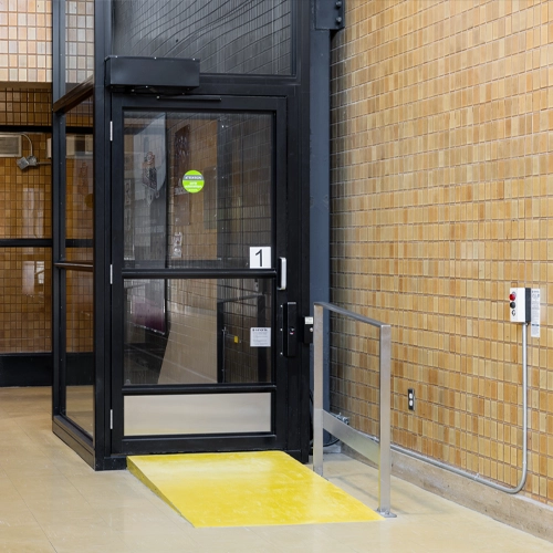 Transparent elevator structure with metal framing and glass panels.