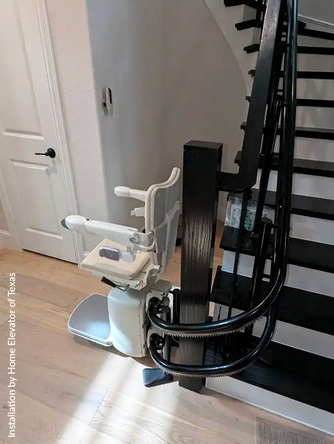 Handicare 4000 stair lift with black rail on a dark staircase