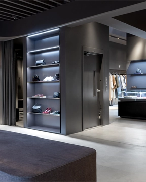 Modern retail interior with dark shelving displays, recessed lighting, and clothing racks arranged throughout the open, minimalist space.