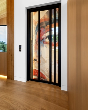 Residential elevator doors with a decorative art panel visible inside the hoistway in a modern hallway