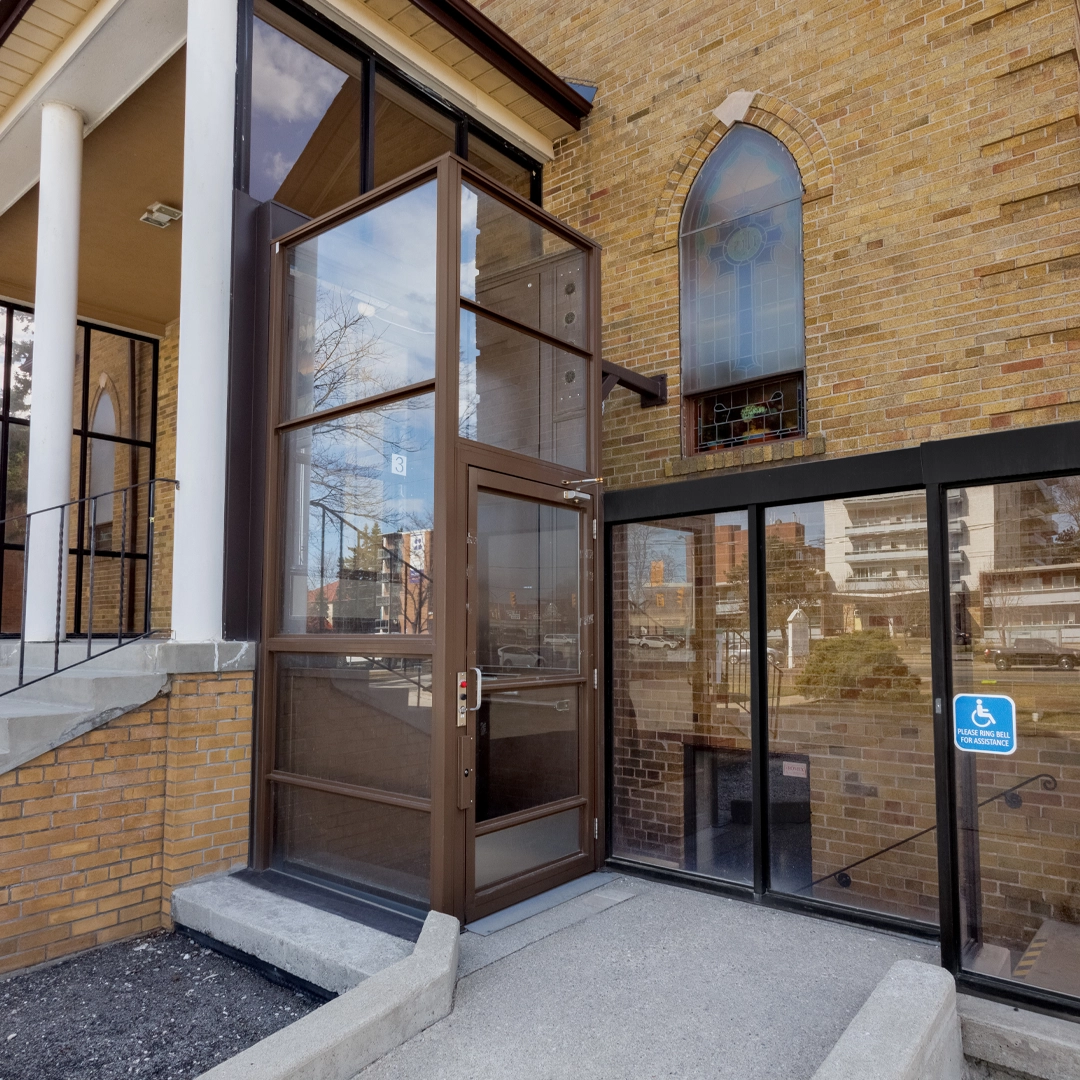 V-1504 Enclosure wheelchair lift near a church entrance, providing barrier-free access with a custom brown finish that complements the building's architecture.